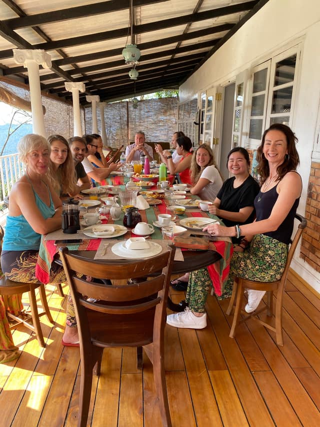 Guests sharing a meal at the long table on the veranda